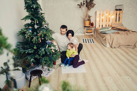 家庭幸福孩子坐在圣诞树旁的一图片