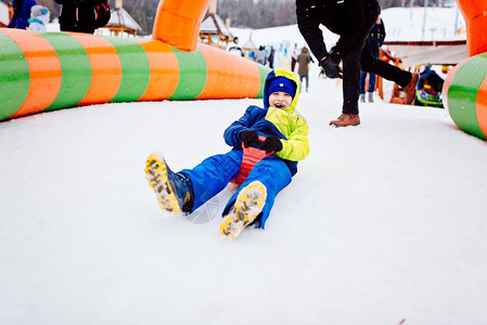 孩子在雪上玩儿得开心滑倒在塑料雪橇图片