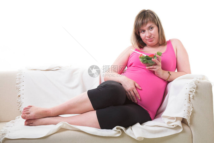 坐在沙发上的孕妇和吃新鲜蔬图片