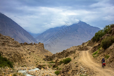 男子在塔吉克斯坦帕米尔山路上骑图片