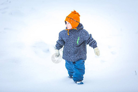 快乐的男孩在冬天在户外玩耍穿着橙色帽子和暖的衣服在冬天户外玩图片