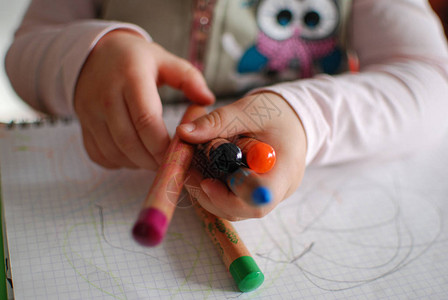 拿着不同颜色蜡笔的儿童手特写图片