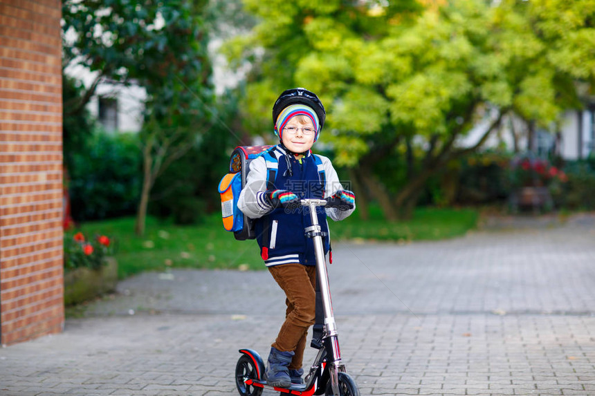 活跃的学校孩子男孩在头盔骑着他的滑板车在城市快乐的孩子穿着五颜六色的衣服骑自行车上学孩子们在户外上图片