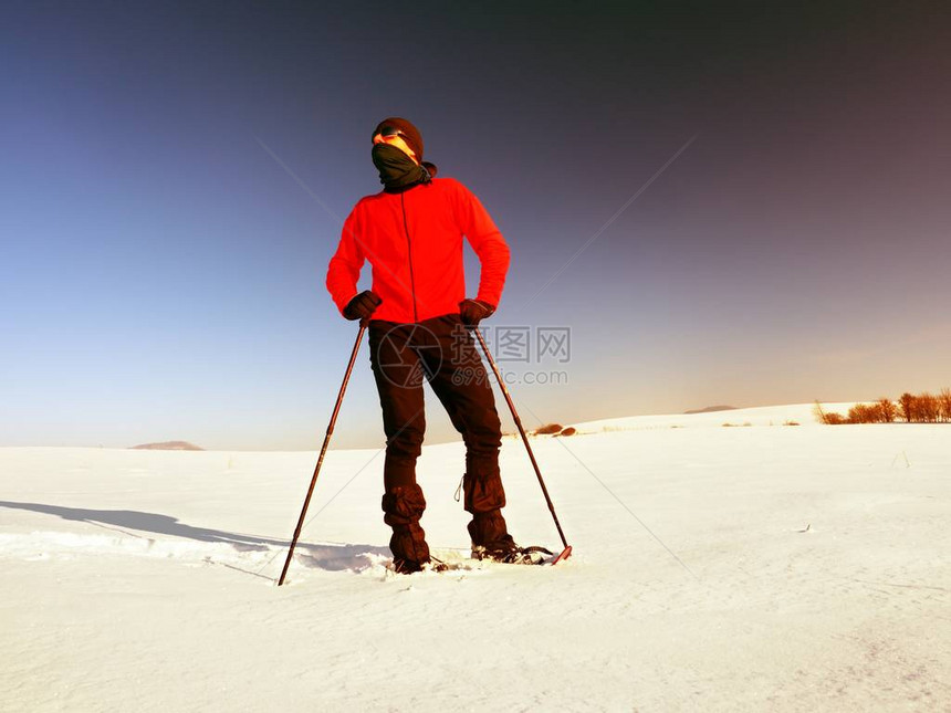 穿着雪鞋的游客在白雪皑的漂流中行走阳光明媚的结冰天气穿着粉红色运动夹克和黑色徒步裤的徒步旅行者在图片