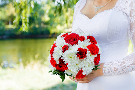 手握着红玫瑰和白菊花的新娘花束图片