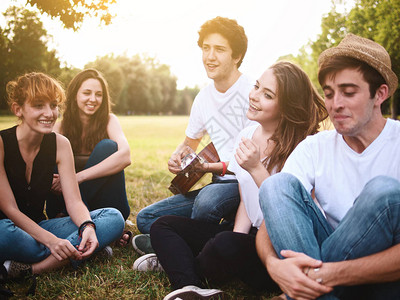 一群年轻朋友在Alfresco野餐弹吉他和公图片