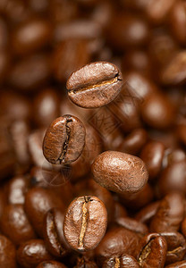 在棕色背景上飞着咖啡豆的宏观照片图片