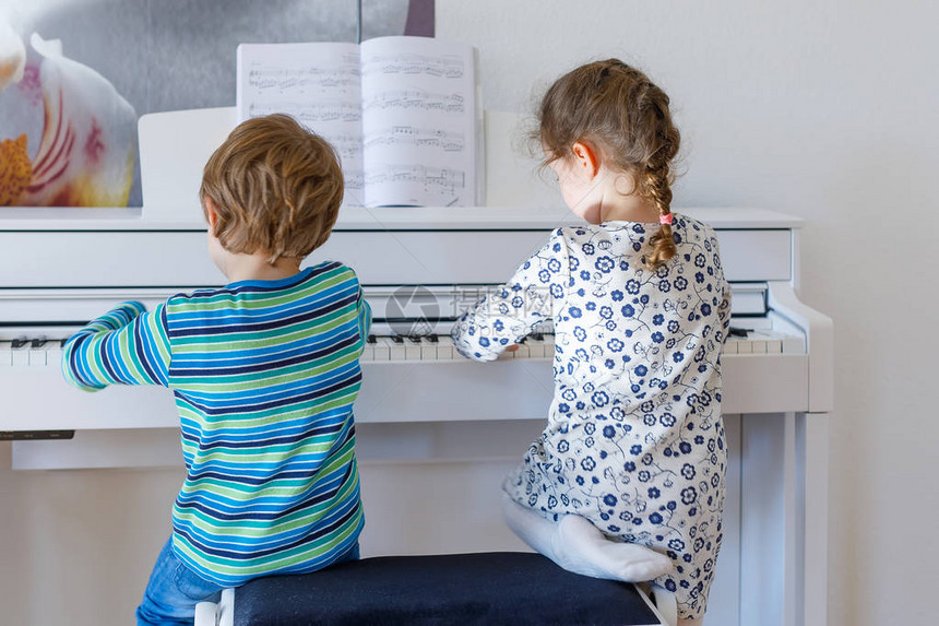两个小孩女和男孩在或音乐学校弹钢琴学龄前儿童在演奏乐器时获得乐趣教图片