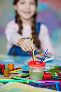小女孩在绘画期间用水将颜漆布料图片