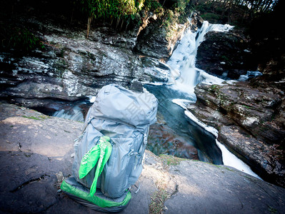 背包坐在瀑布旁的岩石上图片