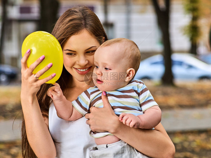 快乐的母亲和她的孩子在夏日公园的户外玩热气球游戏图片