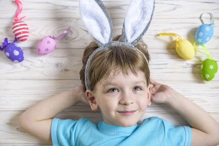 复活节概念快乐的可爱孩子穿耳朵躺在木头背景图片
