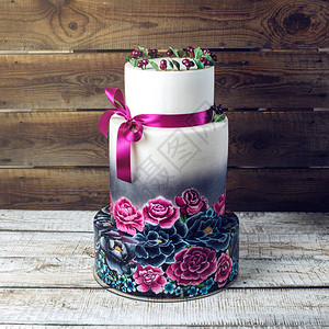 大型婚礼蛋糕装饰在传统的生锈风格的蓝色和紫色玫瑰以及带子中图片