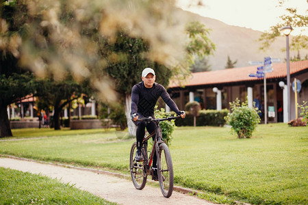 公园的骑马赛车白人成年男子骑自行车穿过图片