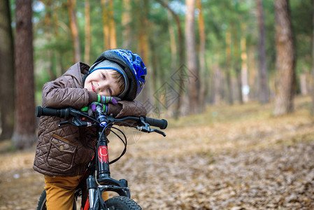 快乐的3或5岁男孩在美丽的秋日骑着自行车在秋天的森林里玩得开心活跃的孩子戴着自行车头盔安全运动休闲背景图片