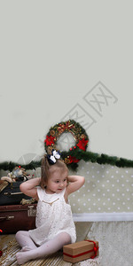 可爱的小女孩穿了圣诞树在房间地背景图片