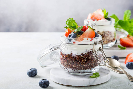 在玻璃罐中配有红quinoa酸奶和浆果的免费早餐健康超食品概念图片