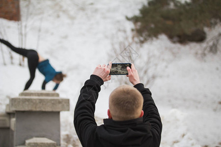 青少年男孩在冬季城市公园Parkour概念的野生动物跳跃女孩智能手图片