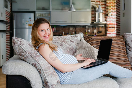 孕妇依靠沙发和笔记本电脑工图片