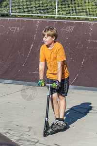男孩在滑板公园骑着他的滑板车玩得很开心图片