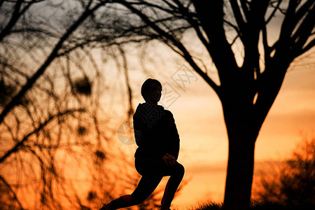 女青年在日出时伸展无边树在跑步前的清晨图片