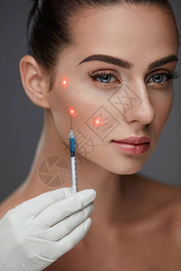 皮肤护理手拿着注射器靠近感的年轻女病人的脸特写美丽的女人接受透明质酸图片