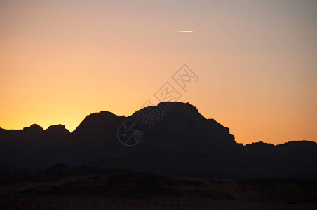 在瓦迪鲁姆山沙漠中一座山的黑暗面上发生烈日落图片