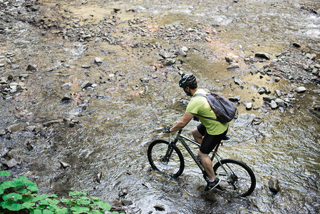 青年运动员穿着头盔骑自行车穿越山河图片