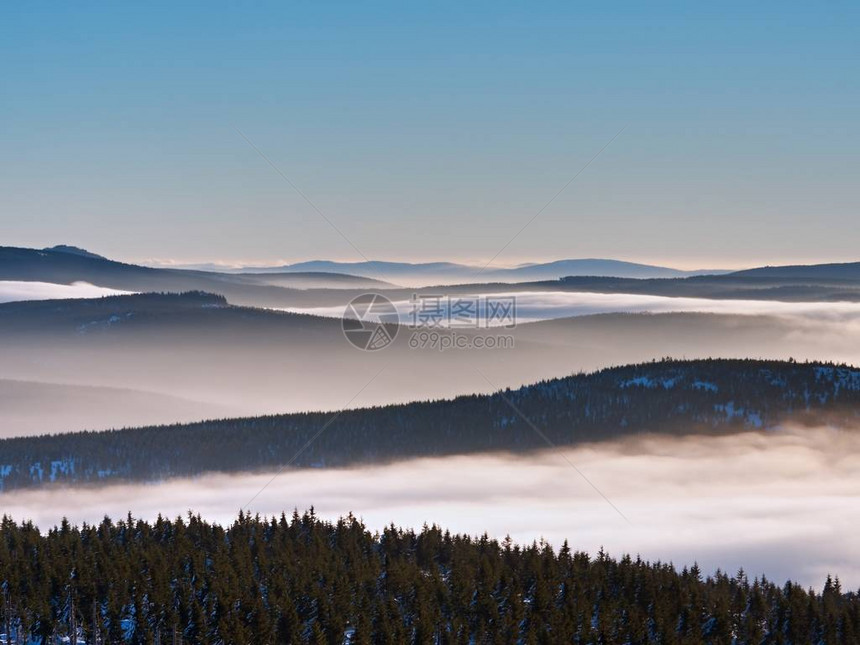 冬天山的迷雾笼罩的山谷奶油薄雾之上的山峰图片