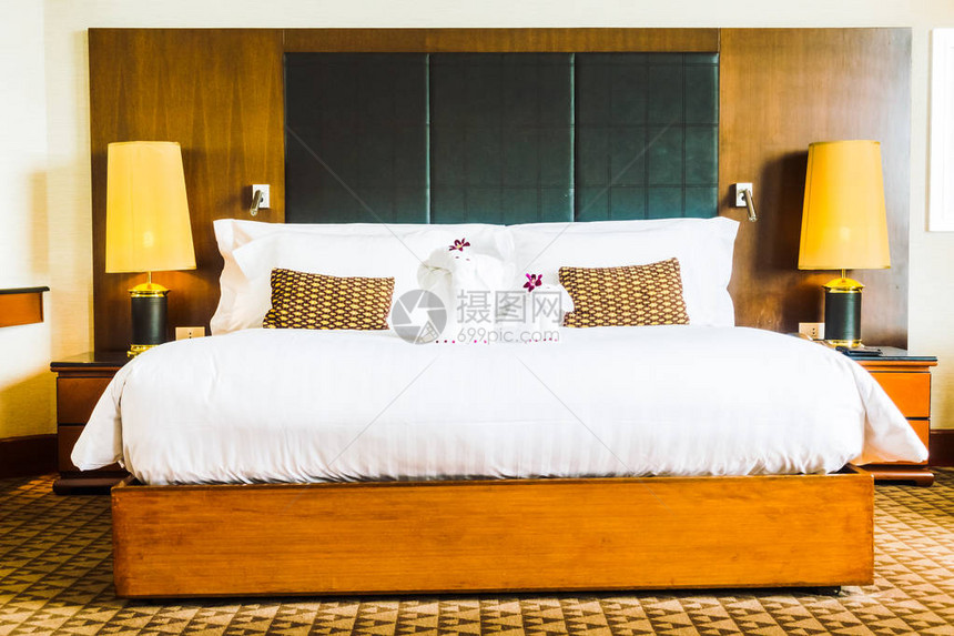 床上漂亮的豪华白色枕头和酒店卧室内部装饰旁边的灯图片