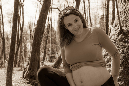 年轻孕妇在公园里摆姿势期待母图片