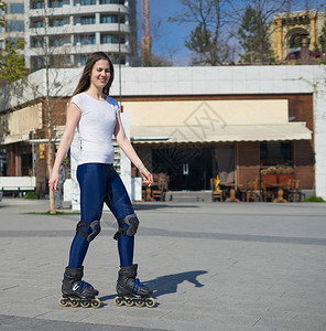 美丽而快乐的轮滑女孩在公园里滑冰图片