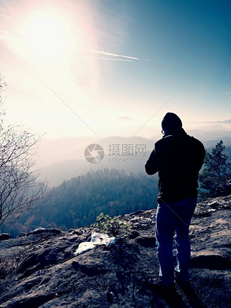 高个子男人正在用脖子上的镜子相机拍照白雪皑的岩石山峰专业摄影师在白雪皑的岩石峰顶用图片