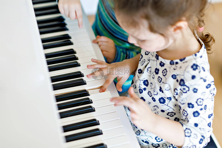 两个小孩女和男孩在或音乐学校弹钢琴学龄前儿童在学习演奏乐器时获得乐趣教图片