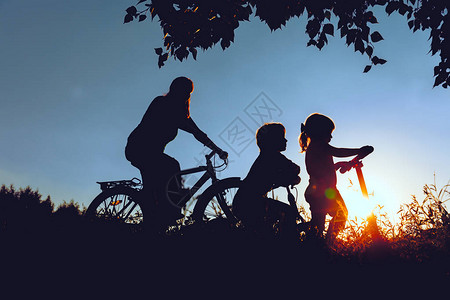 母亲带着儿子和女儿在日落大自然中骑自图片