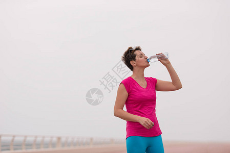健身女人在海边长廊跑步后喝水图片