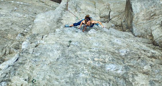 女人攀岩者爬上悬崖攀岩者攀爬在岩壁上图片