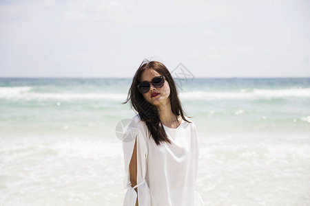 穿白裙子的年轻美女在热带沙滩上戴墨背景图片