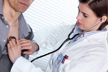 年轻女医生在男病人身上用听诊器听心跳或肺声图片