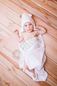 有棕色眼睛的男孩婴儿5个月大了被包在白毛巾里耳朵放在木图片