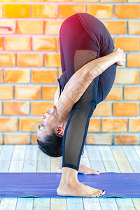 亚裔实习强力女子在具体背景中练习困难的瑜伽拉贾卡波塔图片
