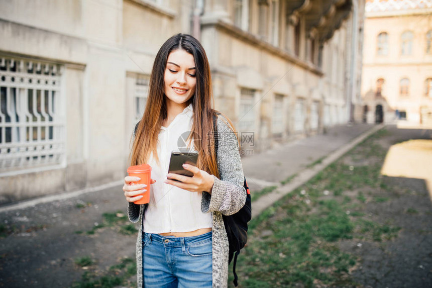 站在街上喝咖啡去用手机的年轻女图片