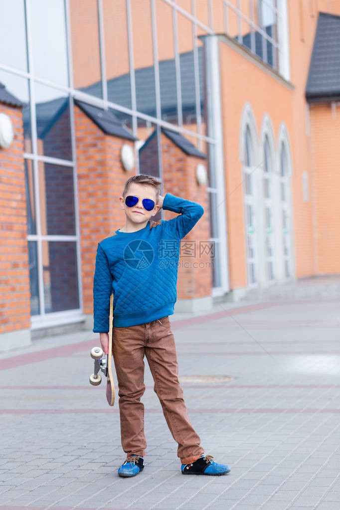 一个美丽的年轻金发男孩在户外购物中心附近的太阳镜的肖像英俊的小男孩在太阳镜与滑图片