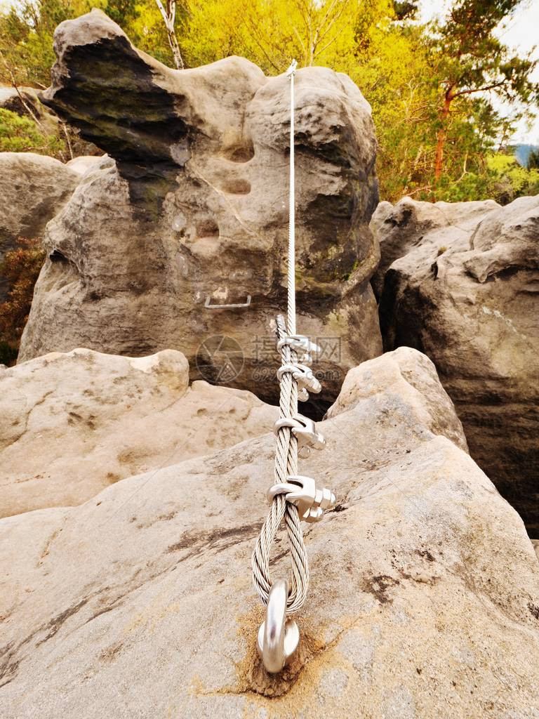 铁绞绳在攀岩者通过铁索攀登的岩石之间伸展绳索通过螺钉卡钩固定在块中锚定在砂岩石图片