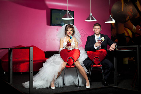 这对夫妇在婚礼当天坐在红色椅子上图片