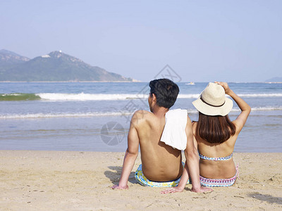 年轻的年轻夫妇情侣坐在海图片