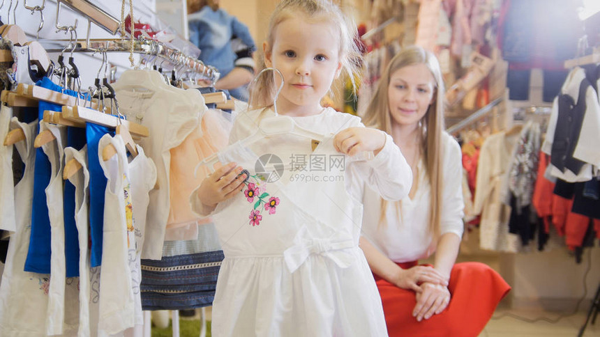 在儿童服装店的手中穿着白光夏装衣服的小女孩特指图片