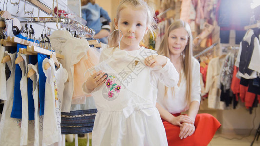 在儿童服装店的手中穿着白光夏装衣服的小女孩特指图片