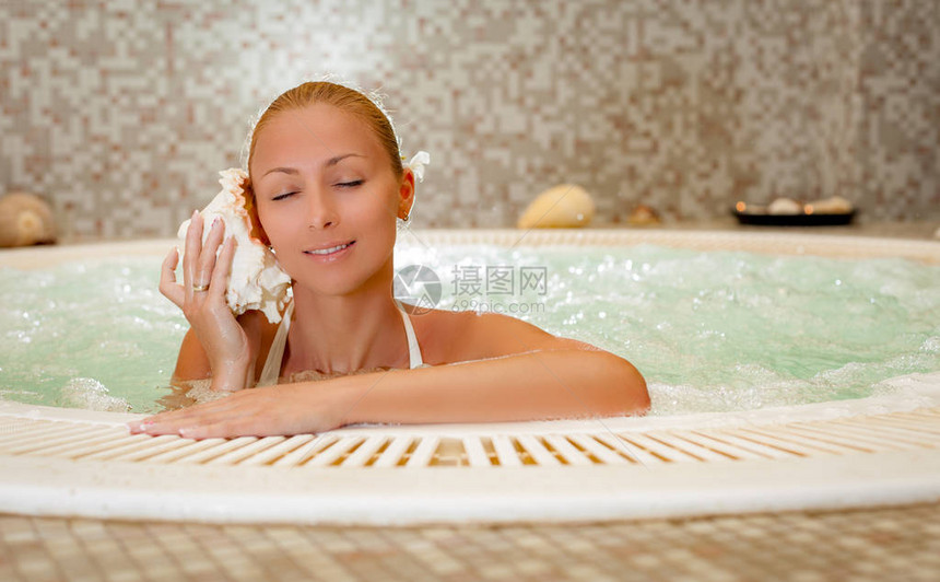 美丽的女人享受和放松在按摩浴图片