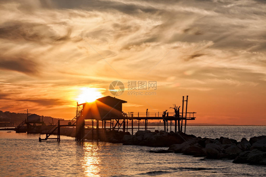 在的夕阳下海上的高跷房子在背光下图片